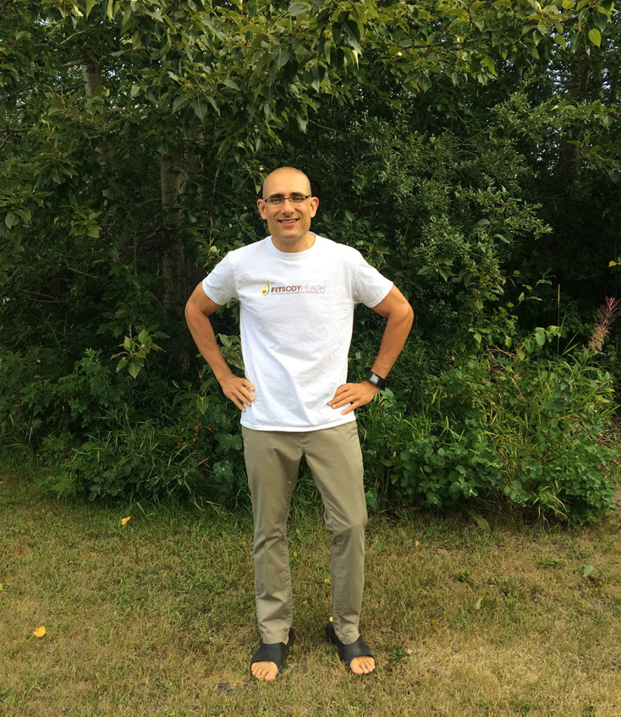 Smiling man in Fitbody Health shirt standing outdoors