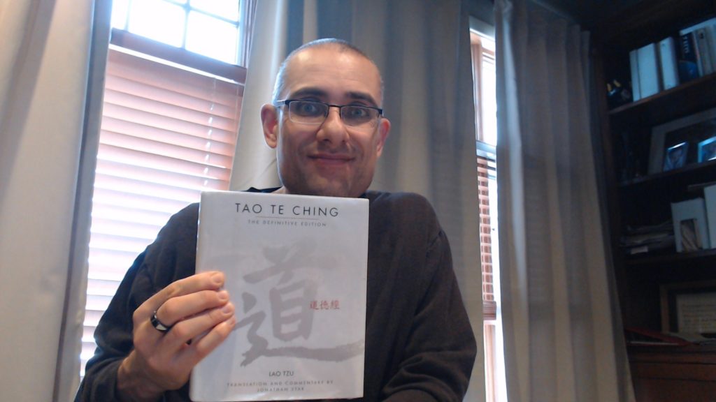 Man holding a copy of Tao Te Ching