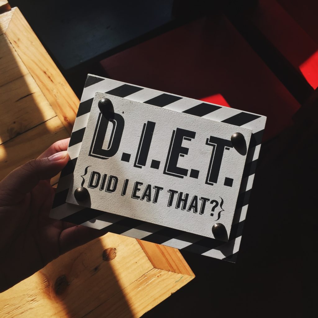 Hand holding clapperboard reading “D.I.E.T. Did I Eat That?”