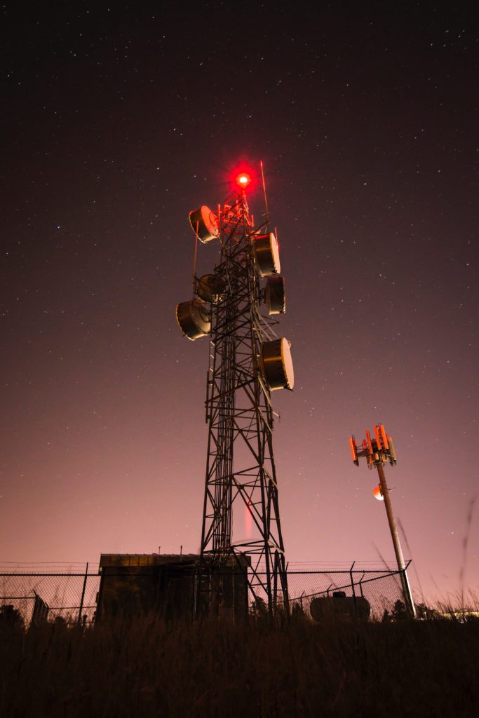 Red-lit communication tower beneath a starry night sky