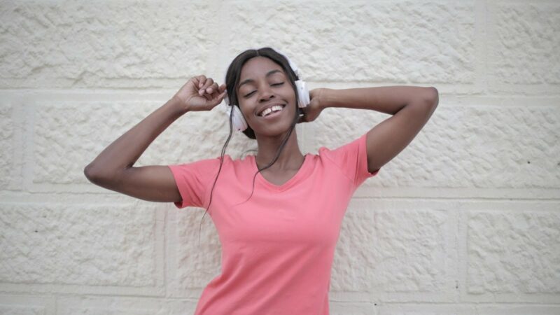 Smiling woman in pink shirt listening to headphones