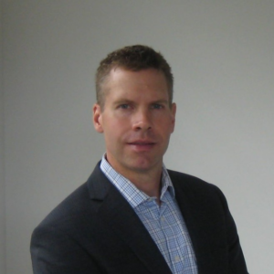 Professional headshot of man in suit and checkered shirt