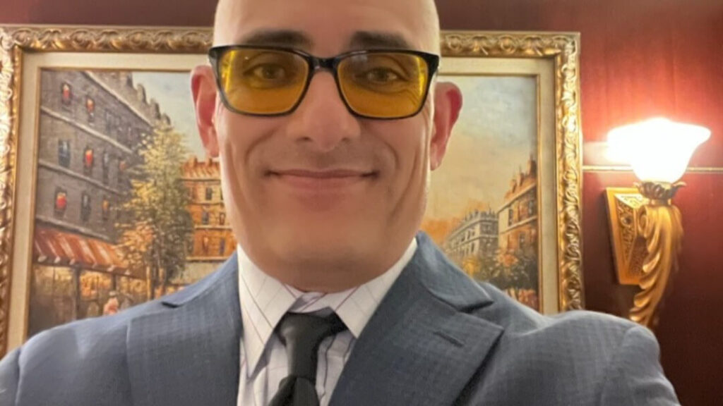 Smiling man in suit wearing yellow-tinted glasses