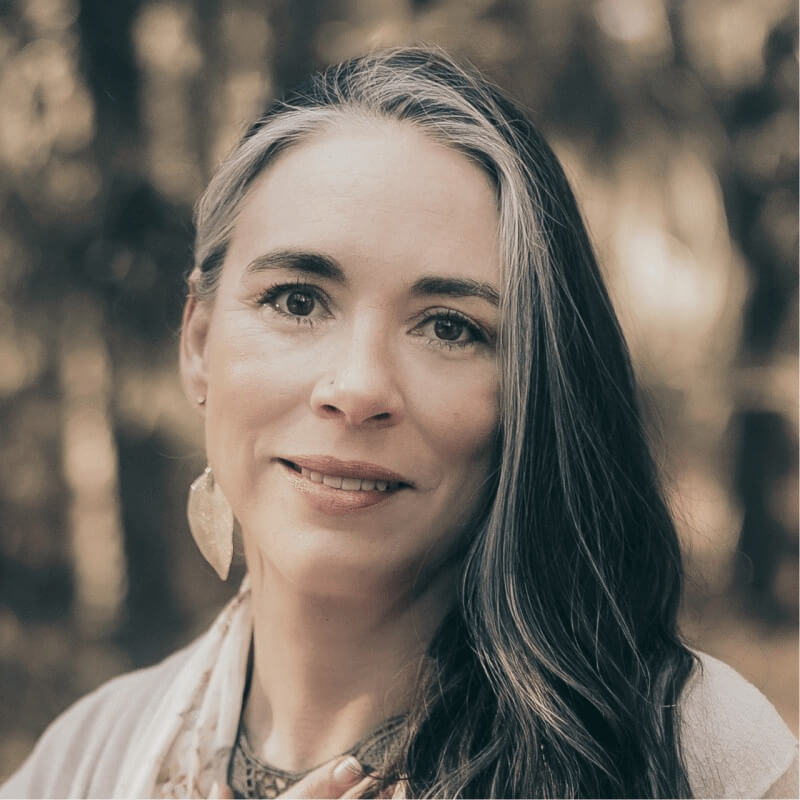 Smiling woman with long gray-streaked hair outdoors